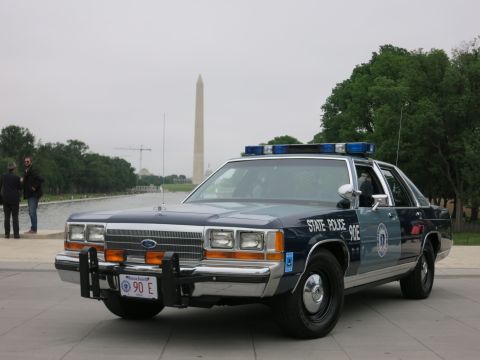 1991 Ford LTD Crown Victoria - navy and silver "State Police 90E" Ford cruiser with push bar viewed from the front, the Washington Monument rising behind it.