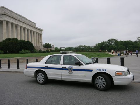 1991 Ford LTD Crown Victoria - white Ford Crown Victoria police sedan with a blue stripe and 'POLICE' lettering parked in front of the columned Lincoln Memorial.