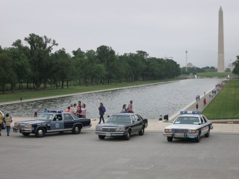 1991 Ford LTD Crown Victoria - Several vintage police and civilian Ford sedans parked along the reflecting pool plaza with onlookers and the Washington Monument in the di…