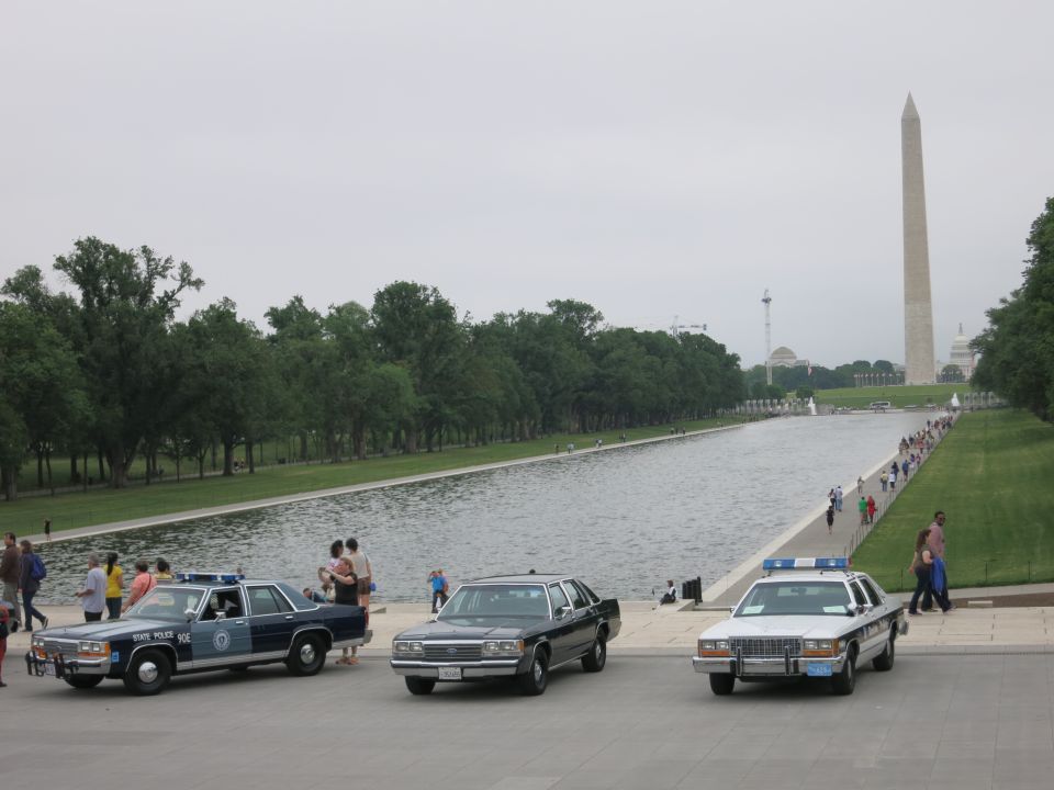 Three vintage sedans parked by reflecting pool, Washington Monument behind