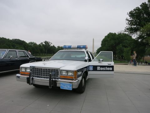 1991 Ford LTD Crown Victoria - Boston Police white and blue Ford sedan with a chrome push bar and roof light bar faces the camera on a plaza.