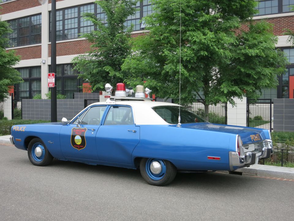 Blue and white 1970s Plymouth police sedan rear three-quarter view