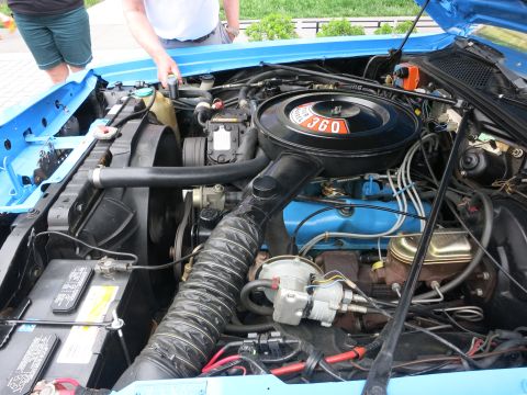 Engine bay of a classic car with a black 360 air cleaner and blue inner fenders