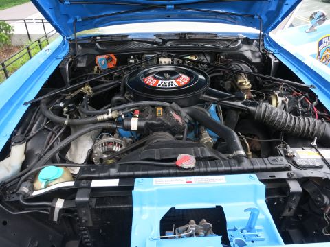 Engine compartment with a black Four Barrel 360 air cleaner and blue painted fenders
