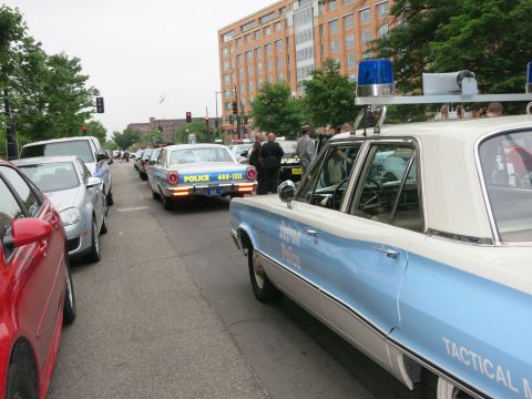 Vintage blue and white Detroit Police sedan parked on a street lined with cars