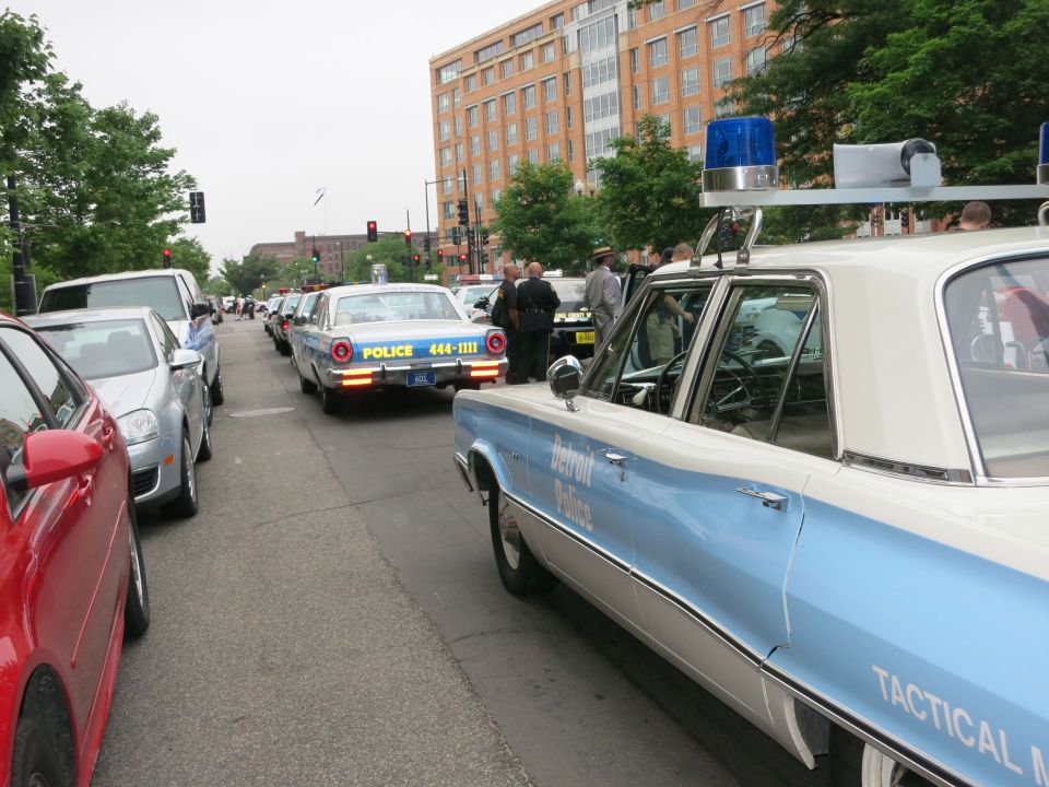 Vintage blue and white Detroit Police sedan parked on a street lined with cars