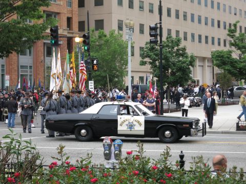 Black and white California Highway Patrol sedan at a parade with honor guard
