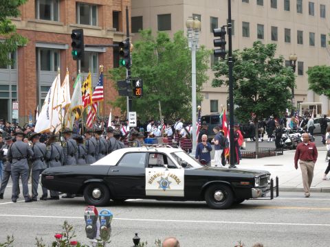 California Highway Patrol black and white sedan at a street ceremony with flags
