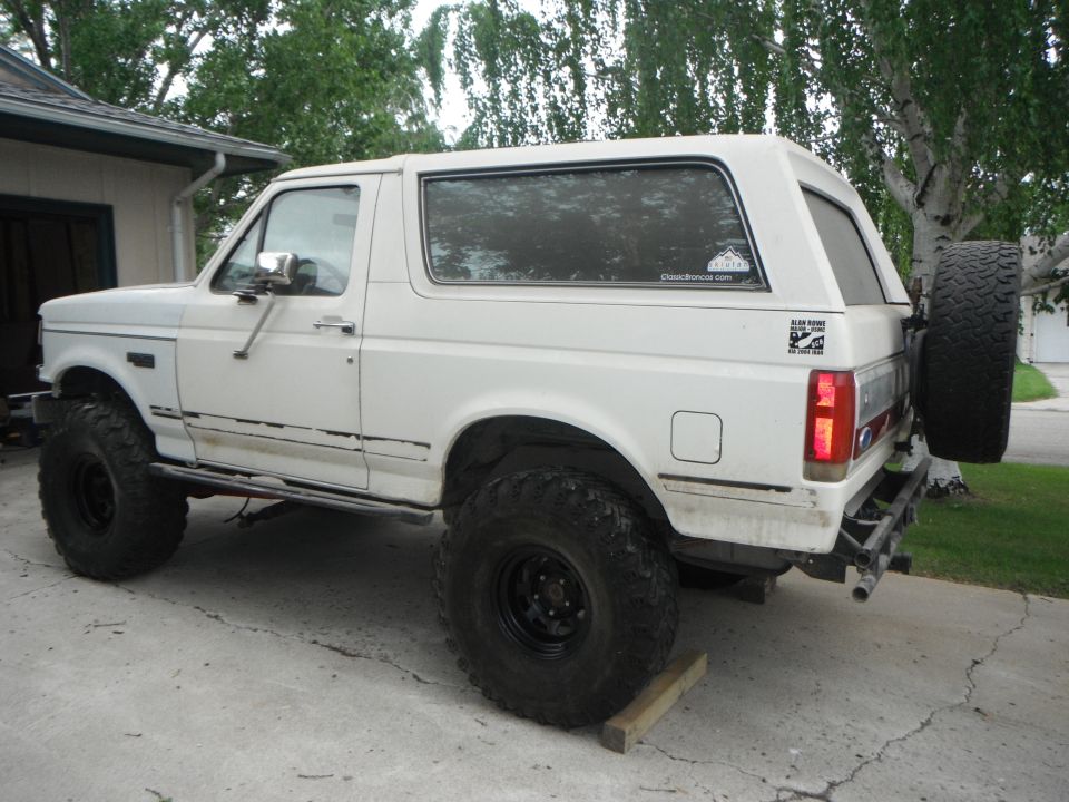 White SUV with large tires and spare tire on rear door, side view