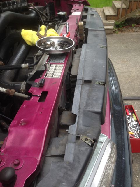 1992 Ford F-150 - Tools and parts laid out on the radiator support of a vehicle's engine bay.