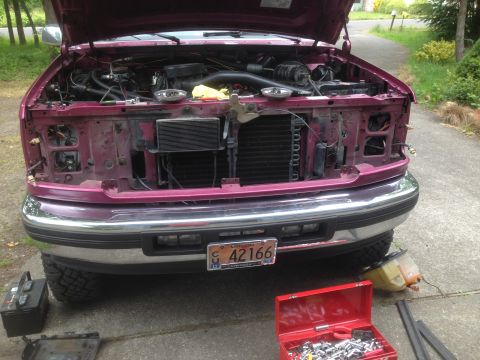 1992 Ford F-150 - The front of a maroon 1992 Ford F-150 is shown with its hood open and parts of the front end disassembled.
