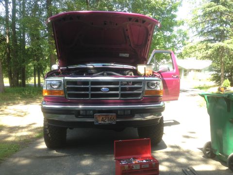 1992 Ford F-150 - A maroon Ford F-150 truck is parked with its hood and driver's door open, revealing a toolbox in front.