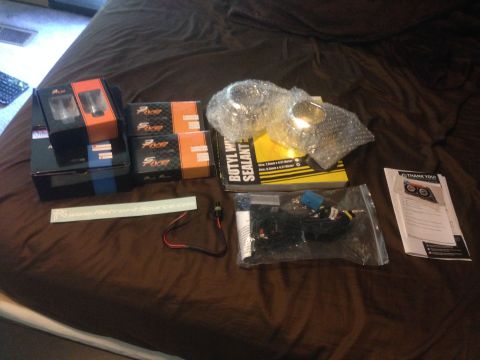 1992 Ford F-150 - Projector headlight retrofit parts including sealant and wiring are laid out on a bedspread.