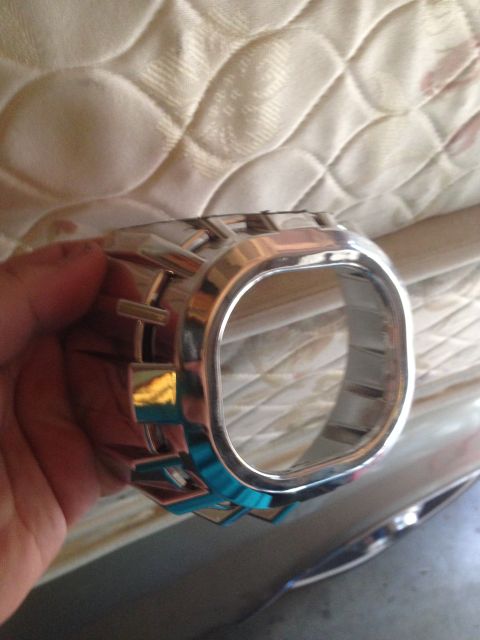 1992 Ford F-150 - A chrome headlight trim ring with blue accents is held in a hand, with a mattress in the background.