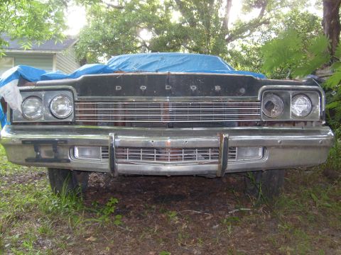 1974 Dodge Monaco - The front grille and headlights of a 1974 Dodge Monaco are visible, partially covered by a blue tarp.