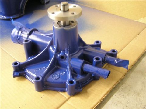 1993 Ford Bronco - A cast-iron water pump freshly painted Ford blue, sitting on cardboard with its bare steel fan/pulley flange and shaft left unpainted. Cast…