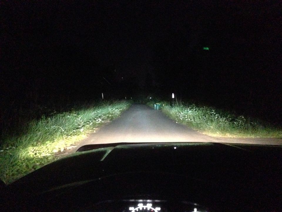 Dashboard view looking out headlights on a dark road at night. Supermotors.net watermark visible