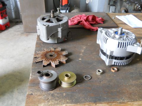 1992 Ford Bronco - Alternators and associated parts laid out on a wooden workbench for inspection or repair.