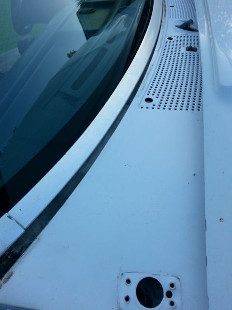 1992 Ford Bronco - Close-up view of the windshield cowl and wiper area on a white vehicle, showing the perforated vent cover.