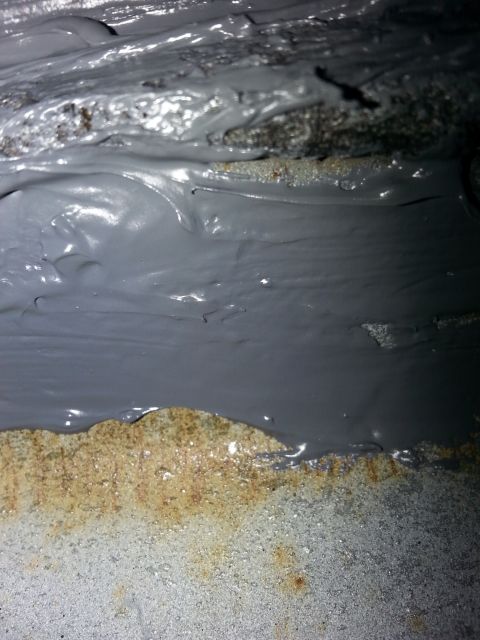 1992 Ford Bronco - Close-up of grey sealant on a rusty metal surface, likely part of a vehicle's undercarriage or engine bay.