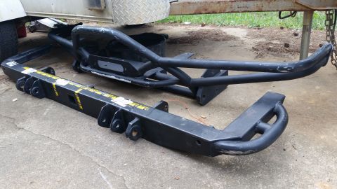 1988 Ford Bronco - Aftermarket bumpers are displayed on a concrete surface next to a trailer.