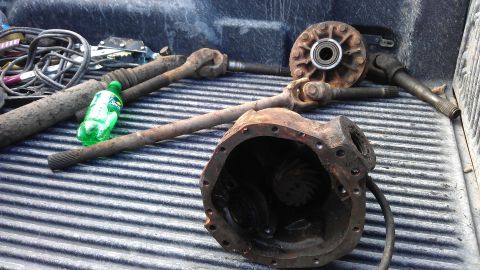 1994 Ford Bronco - Various used differential and axle parts are piled on a truck bed.