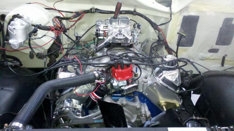 Engine bay of a 1982 Ford Bronco with a V8 engine, chrome accents, and aftermarket carburetor