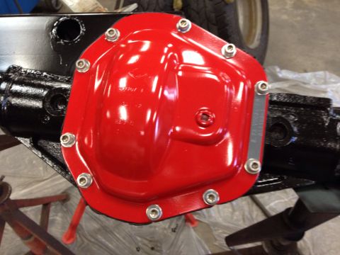 1993 Ford Bronco - A close-up view of a freshly painted red differential cover attached to a black axle assembly.