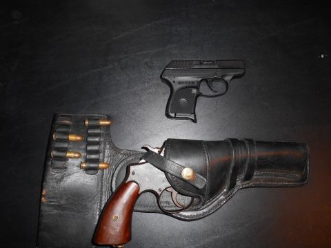 1994 Ford Bronco - A black Ruger pistol and a revolver with a leather holster and ammunition strip are displayed on a dark surface.