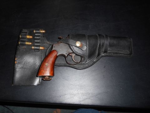 1994 Ford Bronco - A vintage revolver rests in a leather holster, accompanied by a leather ammo belt holding several cartridges.