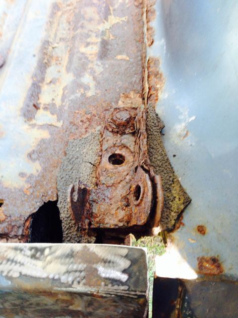 1979 Ford Bronco - Close-up of heavily rusted metal bracket and body panel on a vehicle, showing significant deterioration.