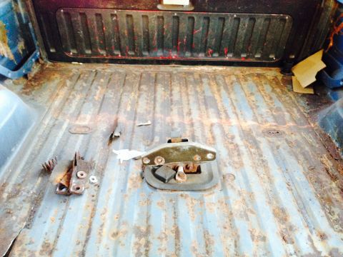 1979 Ford Bronco - Interior of a heavily rusted truck bed, showing the floor and a central tie-down anchor.