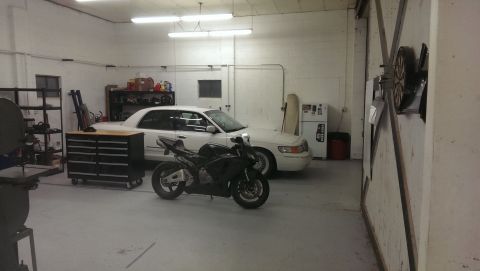 2000 Mercury Grand Marquis - A white 2000 Mercury Grand Marquis is parked in a garage next to a black motorcycle, with various tools and equipment visible.
