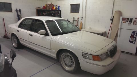 2000 Mercury Grand Marquis - White 2000 Mercury Grand Marquis with aftermarket wheels in a garage setting.