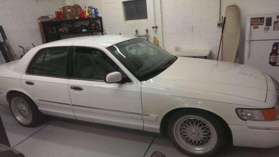 White 2000 Mercury Grand Marquis sedan parked in a garage, showing its front passenger side
