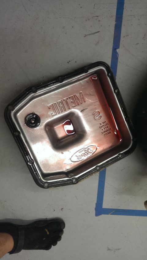 2000 Mercury Grand Marquis - A Ford transmission pan, stamped with "METRIC", contains red fluid.