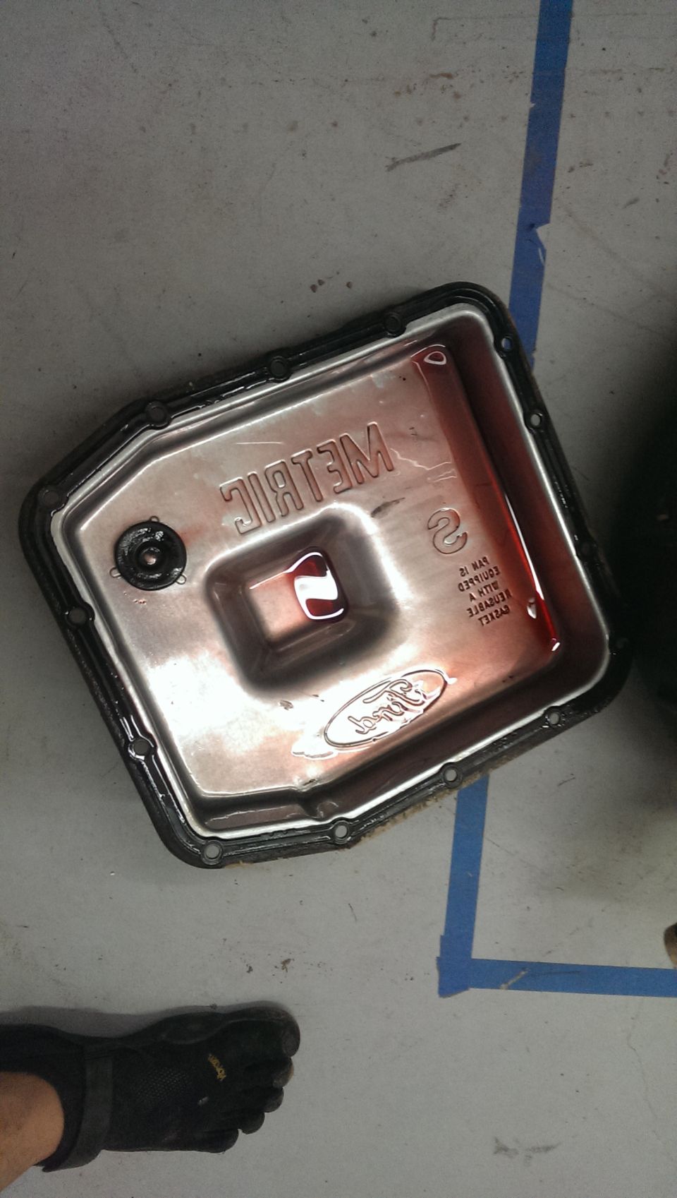 Ford transmission pan with red fluid and "METRIC" stamped on it