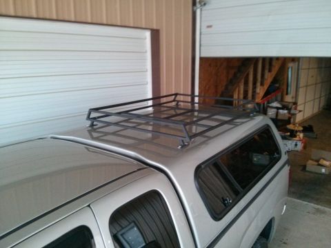 1986 Ford Bronco - A truck is parked inside a garage with a custom roof rack mounted on its cap.