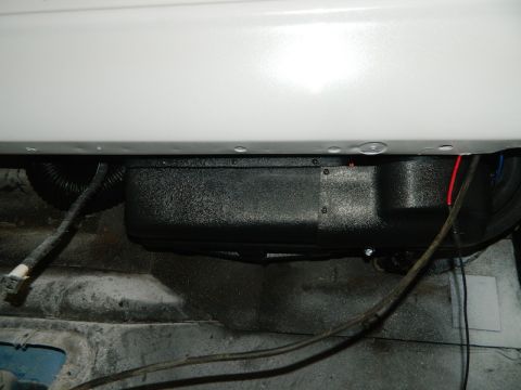 1979 Ford Bronco - An underbody AC unit is visible with associated wiring and tubing, mounted beneath a white vehicle body panel.