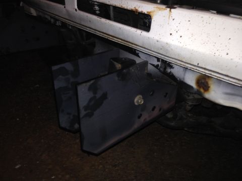 1990 Mitsubishi Montero - A custom bumper bracket is bolted to the frame of a white vehicle, showing signs of rust.