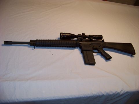1995 Mercury Grand Marquis - A rifle with a scope and extended magazine is displayed on a white surface.