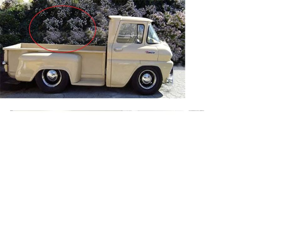 Cream-colored Ford Econoline pickup truck with chrome wheels parked next to flowering bushes