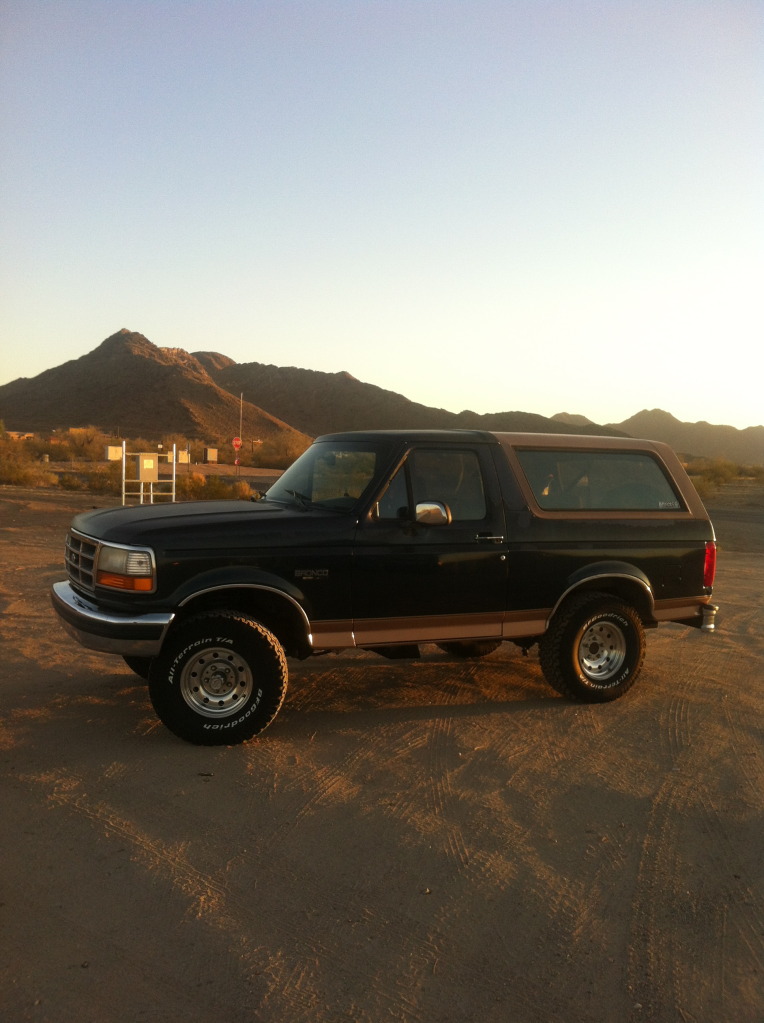 1994 Ford Bronco parked on dirt with mountains in background