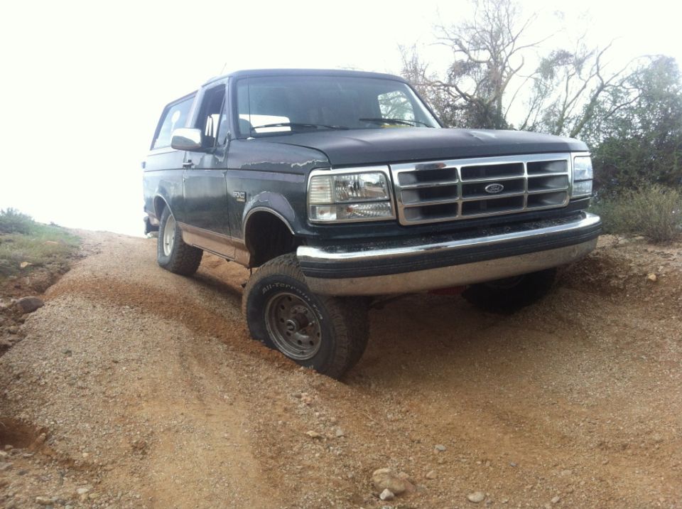 1994 Ford Bronco driving on a dirt road with one front wheel turned