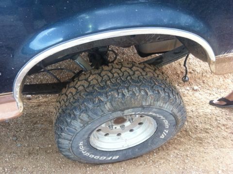 1994 Ford Bronco - The rear tire and suspension system of a dark blue SUV are visible in this close-up shot.