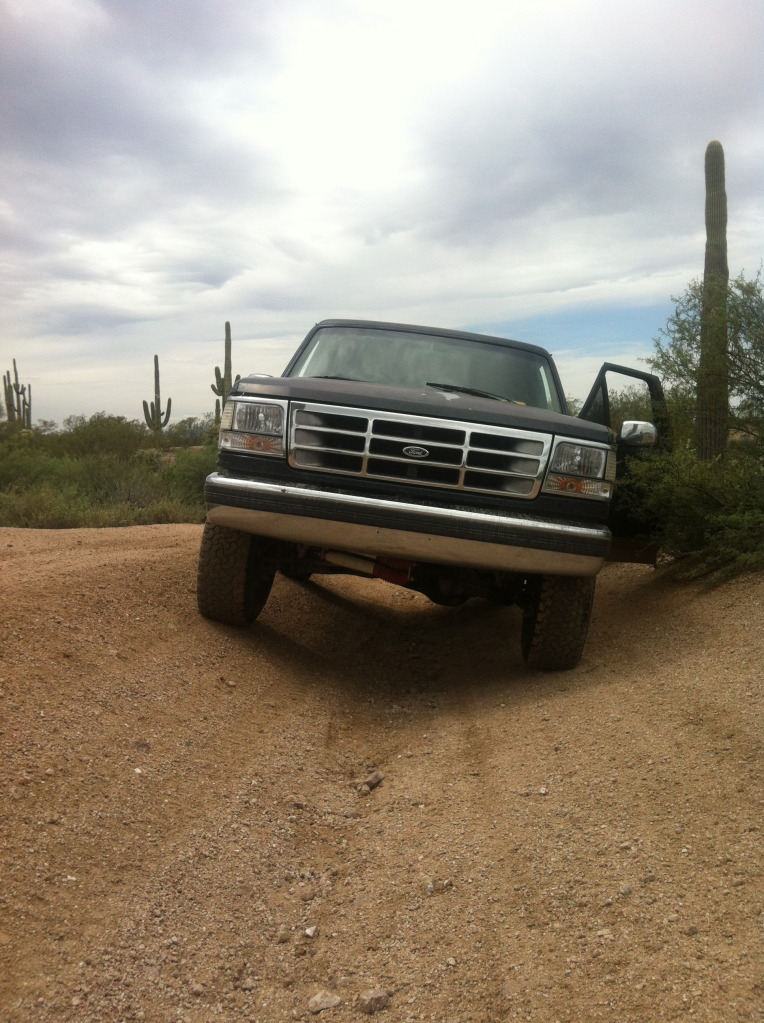 Ford F-Series truck with door open, parked on a dirt road in a desert landscape with saguaro cacti