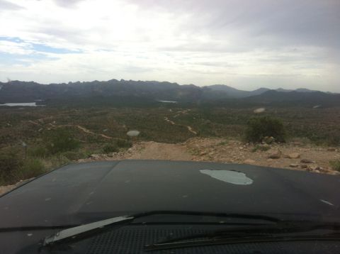 1994 Ford Bronco - View from inside a vehicle driving on a dirt road through a , mountainous terrain.