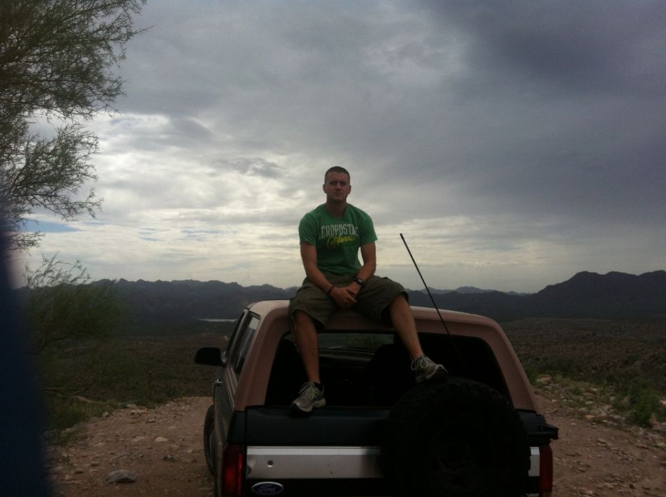 1994 Ford Bronco with a man sitting on the tailgate, overlooking a mountain landscape