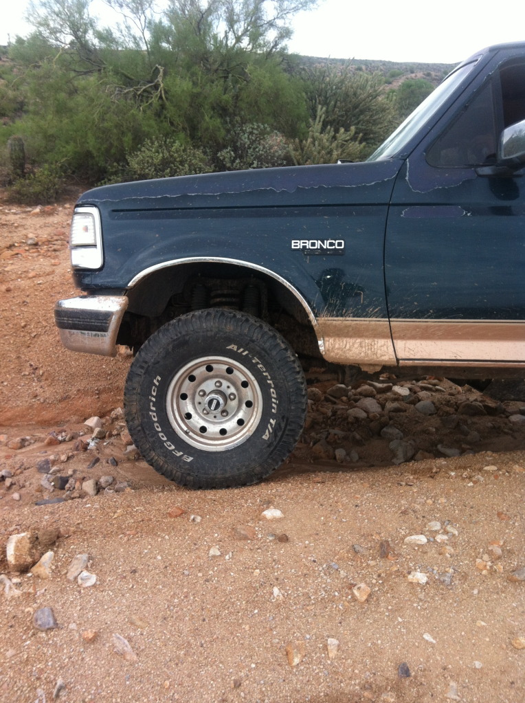 Dark blue Ford Bronco with tan lower trim, off-road tire, and peeling paint on hood