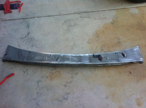 1994 Ford Bronco - A metal windshield wiper cowl panel is shown on a concrete surface, with a red brush nearby.